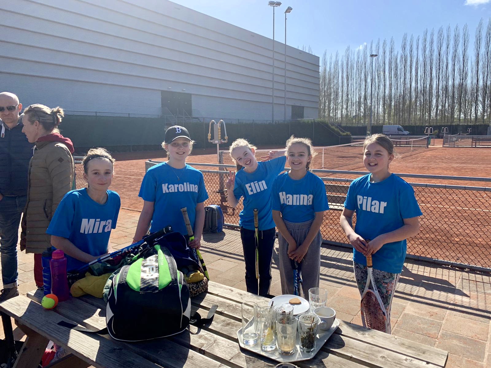 Een groep meisjes bij de tennisbaan